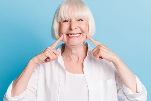 Photo portrait of granny blonde hair pointing at white teeth healthy smile dental whitening veneers isolated on bright blue color background